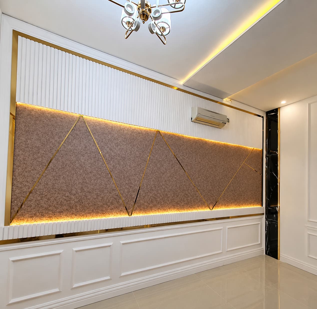 White panelled living room wall with a patterned brown centre section and gold trim running in a zigzag