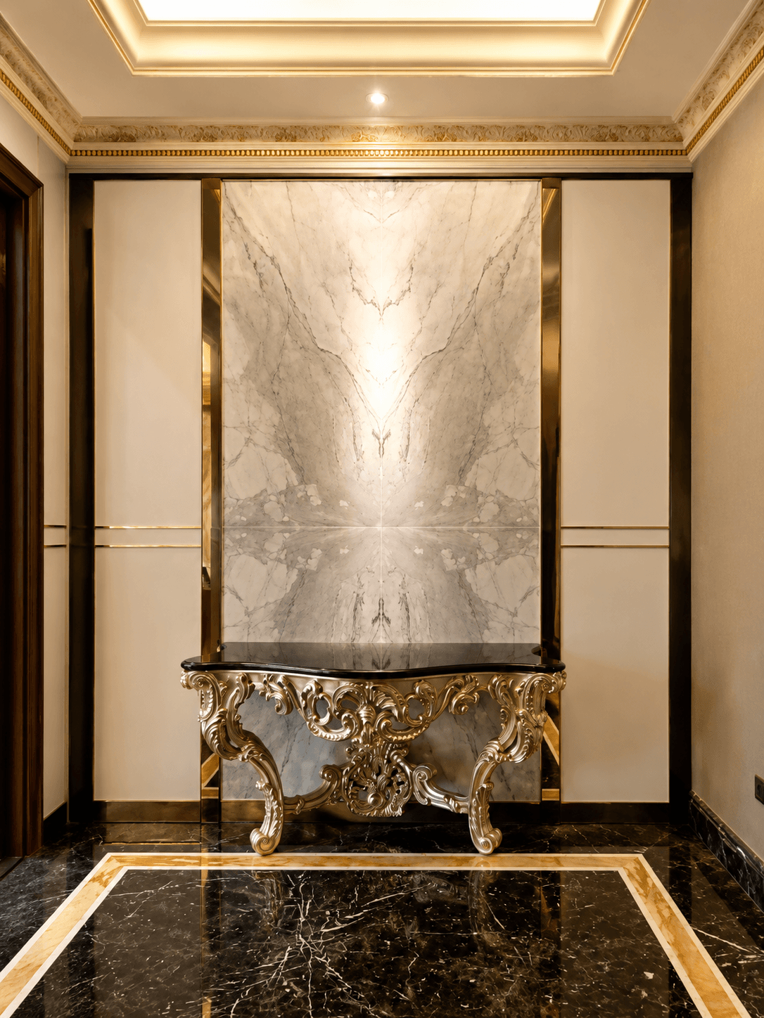 White marble foyer with gold stainless framing the wall panels, a carved gilt console with a black top, and black marble floors inlaid with gold
